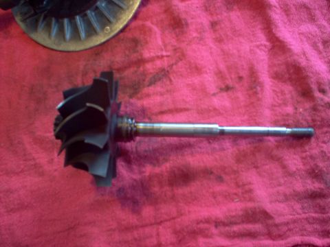 1996 Ford Probe - A close-up view of a turbocharger's turbine wheel and shaft assembly, resting on a red fabric surface.