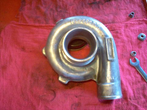 1996 Ford Probe - A turbocharger housing sits on a red cloth next to a wrench and nuts, showing visible markings.