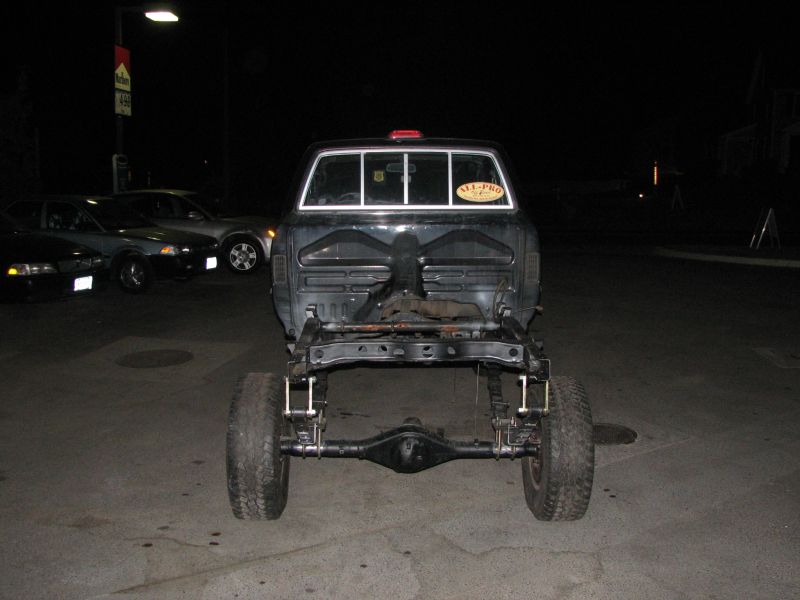 1994 Toyota Tacoma chassis viewed from rear at night, with other cars parked nearby