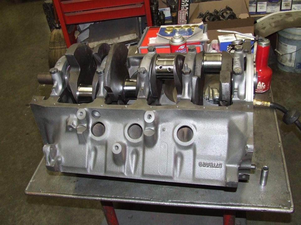 Engine block with crankshaft on a metal table, with tools and parts in the background