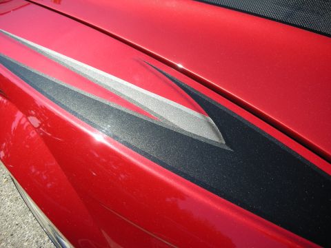1998 Ford Crown Victoria - A red car features custom black and silver racing stripes on its side panel.