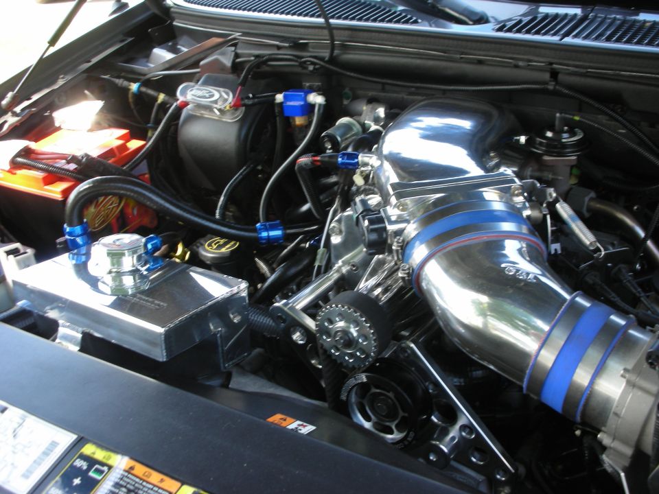 Engine bay with chrome supercharger, blue hose clamps, and custom coolant reservoir