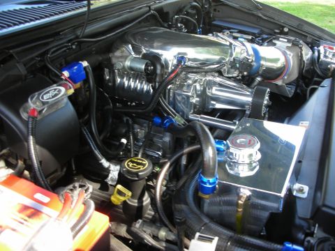 1998 Ford Crown Victoria - Close-up of a modified engine bay a polished supercharger and custom plumbing.