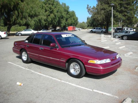 1998 Ford Crown Victoria - A maroon sedan is parked in a lot with other vehicles visible in the background.