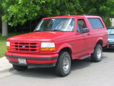 2001 Harley-Davidson Sportster Custom - A red Ford Bronco is parked on a residential street with trees in the background.