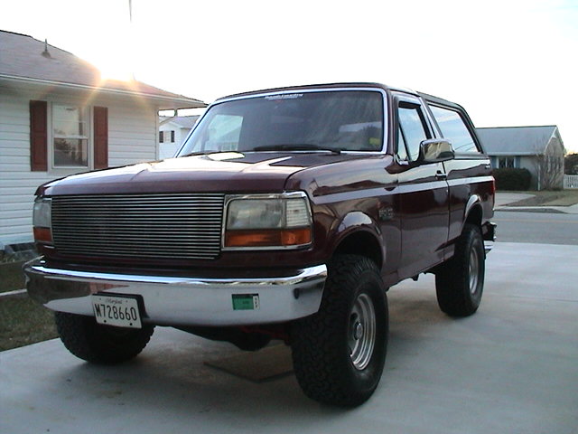 Maroon 1990s Ford Bronco with billet grille, front three-quarter in a driveway