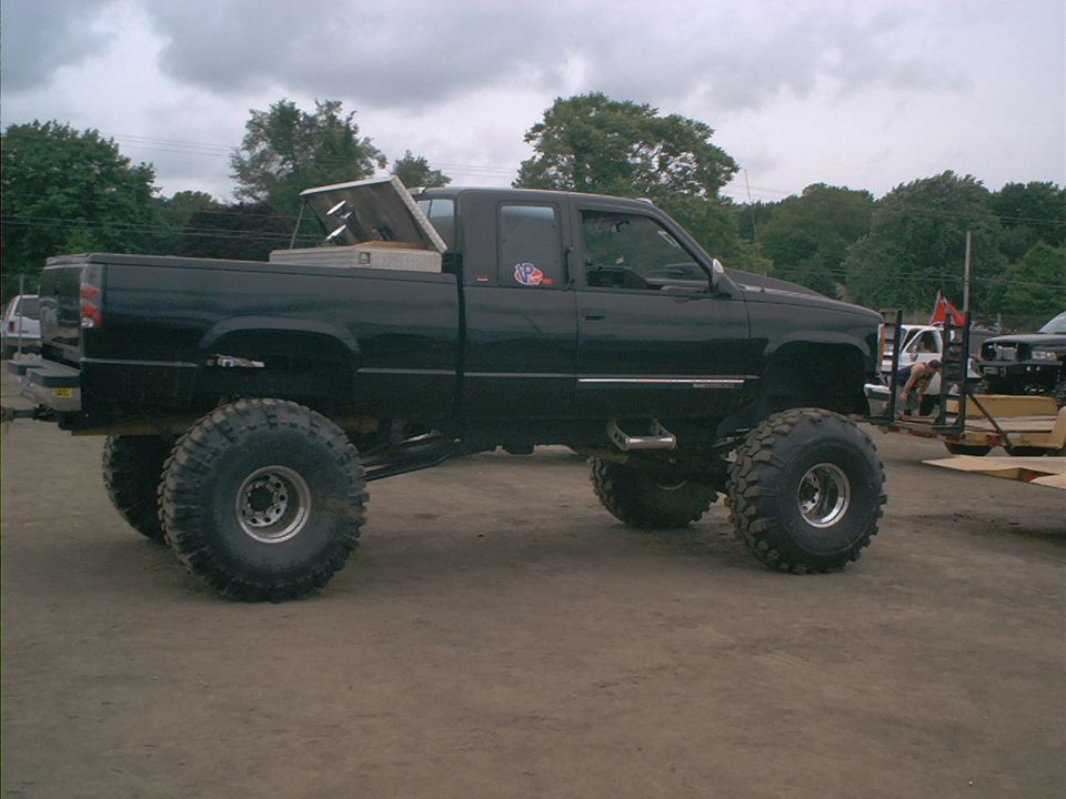 Black lifted pickup truck with large tires and a toolbox in the bed