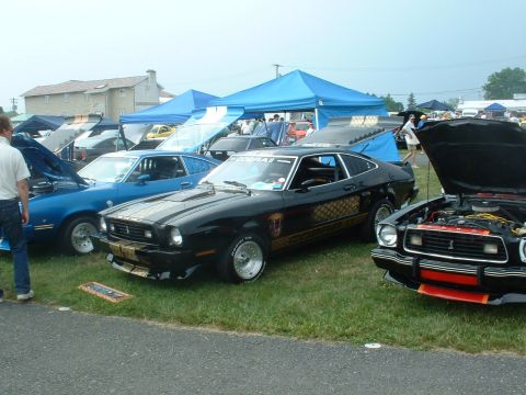 1978 Ford Mustang II - Several cars are on display at an outdoor event, including a black 1978 Ford Mustang II Cobra II.