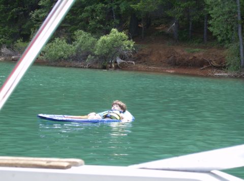 1986 Ford Bronco - A person relaxes on a flotation device in a calm, green lake surrounded by trees.
