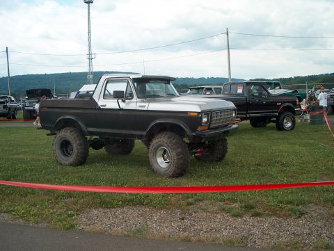 1978 Ford Bronco - A modified pickup truck with a two-tone paint scheme and large off-road tires is displayed outdoors.