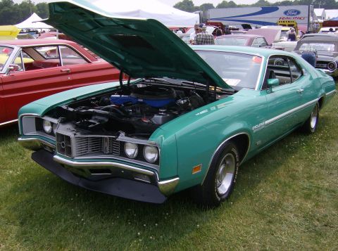 1970 Ford Ranchero - A green 1970 Mercury Cyclone is displayed with its hood open at an outdoor event, with other vehicles visible in the background.