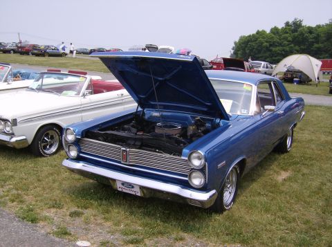 1970 Ford Ranchero - Blue 1967 Mercury Cougar XR7 at a car show, hood open. Another classic car is parked beside it.