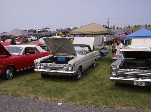 1970 Ford Ranchero - A beige 1964 Ford Falcon convertible is displayed with its hood open at an outdoor car show.