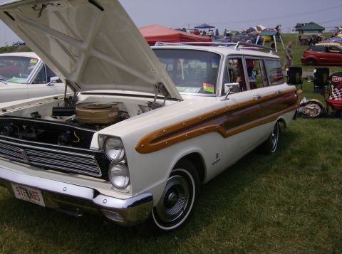 1970 Ford Ranchero - This wood-paneled station wagon, likely a 1965 model, is displayed with its hood open at an outdoor event.