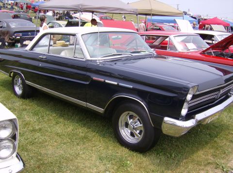 1970 Ford Ranchero - A dark blue coupe with a white roof is parked on grass at an outdoor car show.