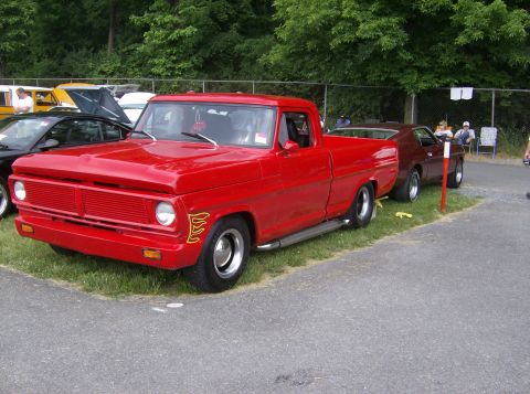 1970 Ford Ranchero - A red 1970 Ford Ranchero pickup truck with flame decals is parked on grass next to another vehicle.