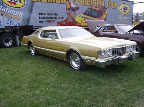 1970 Ford Ranchero - A two-tone 1977 Ford Thunderbird is parked on a grassy area with a trailer and another vehicle in the background.