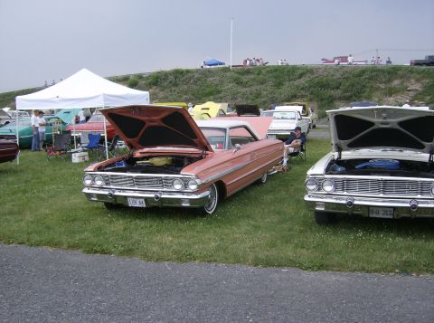 1970 Ford Ranchero - A pink 1964 coupe, possibly a Ford Galaxie, is displayed with its hood open at an outdoor car show.