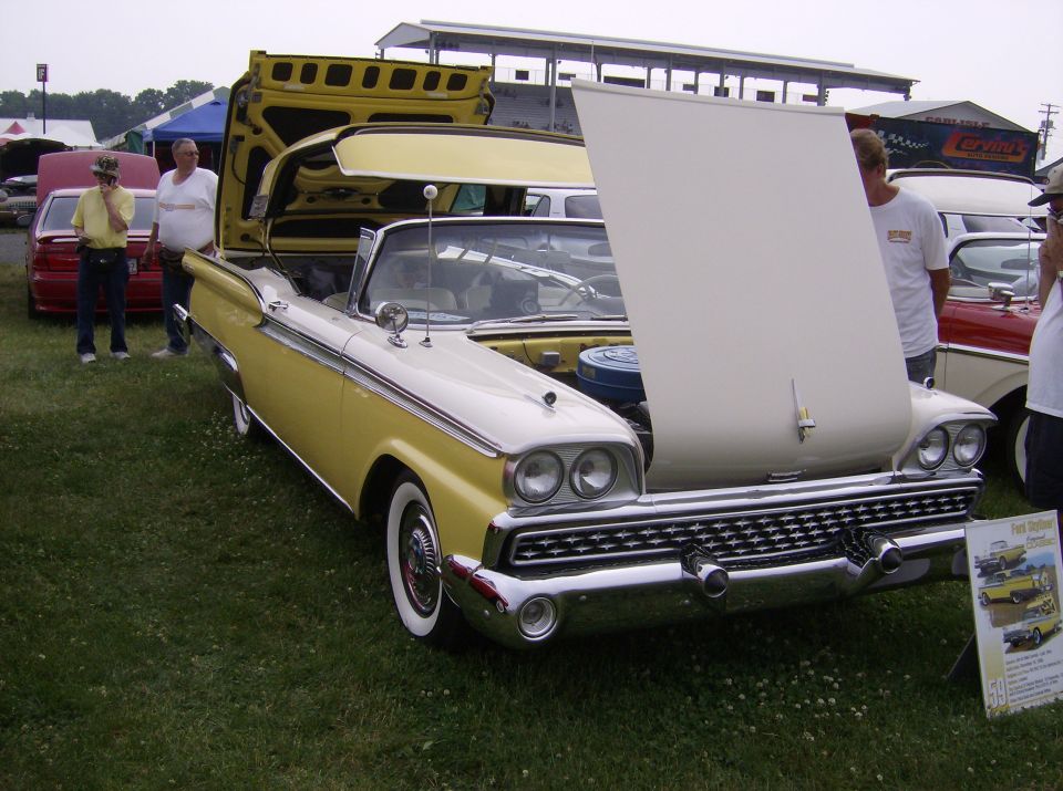 Yellow and white 1959 Ford Fairlane 500 Skyliner with hood and trunk open. Another car is visible behind it