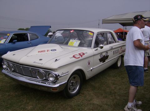 1970 Ford Ranchero - A white Mercury Comet race car is parked on grass next to a blue car under a cloudy sky.