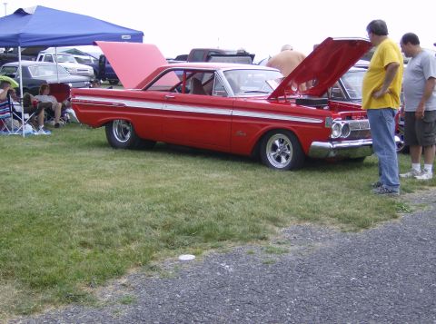 1970 Ford Ranchero - A red 1963 Mercury Comet is displayed with its hood open, attracting attention from onlookers.