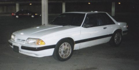 1992 Ford Mustang - A white coupe with black trim and aftermarket wheels is parked in a garage, with another car visible in the background.