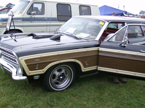 1970 Ford Ranchero - This 1967 Ford Country Sedan station wagon features wood paneling and a hood scoop. A white van is visible behind it.