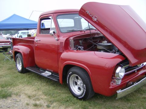 1970 Ford Ranchero - A classic red Ford F-100 pickup truck is displayed with its hood open, revealing the engine compartment.