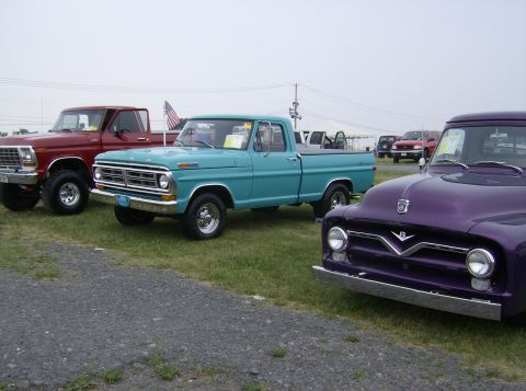 1970 Ford Ranchero - A row of classic pickup trucks, including a teal model from the 1970s, are displayed outdoors.