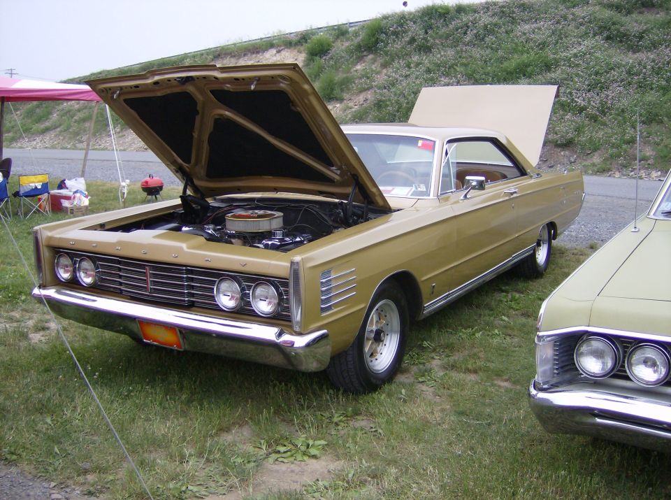 1967 Mercury Cougar with hood open, parked next to another car