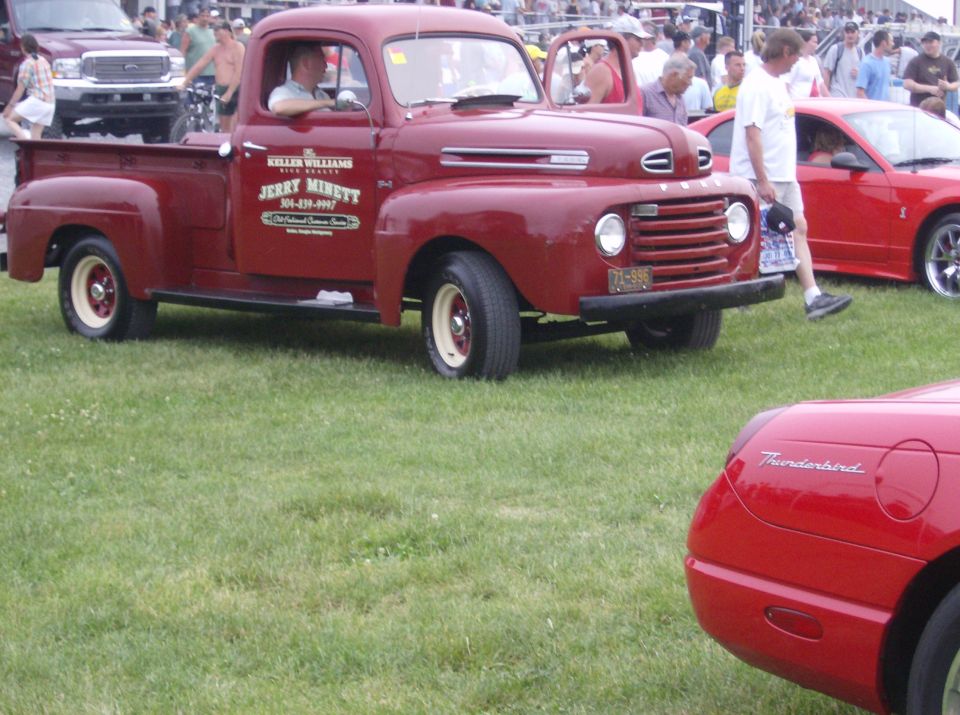 Red pickup truck with "KELLER WILLIAMS JERRY MINETT" text on door, parked on grass