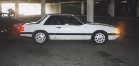 1992 Ford Mustang - A white Ford Mustang is parked in a dimly lit garage, with another vehicle visible to its left.