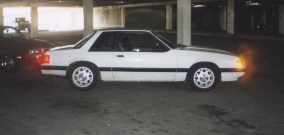 White Fox-body Ford Mustang notchback coupe side view in a parking garage