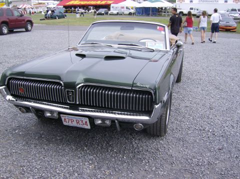 1970 Ford Ranchero - A green 1969 Mercury Cougar convertible is shown from the front at an outdoor event with other vehicles and tents in the background.