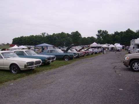 1970 Ford Ranchero - A variety of vintage automobiles are displayed at an outdoor gathering, with tents and recreational vehicles visible.