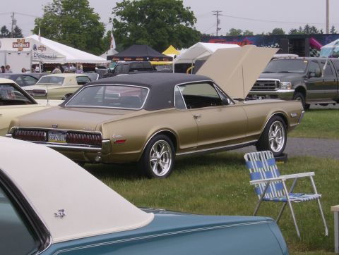 1970 Ford Ranchero - A gold 1968 Mercury Cougar XR7 is displayed with its hood open at an outdoor event, parked on grass.