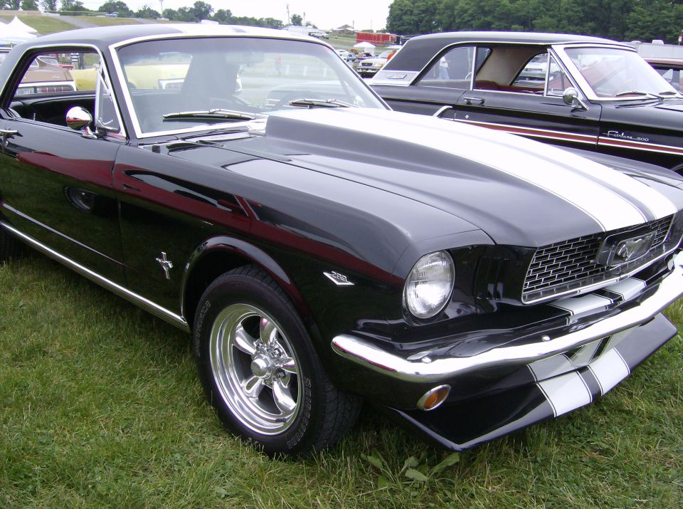 Black 1965 Ford Mustang with white racing stripes and scoop hood