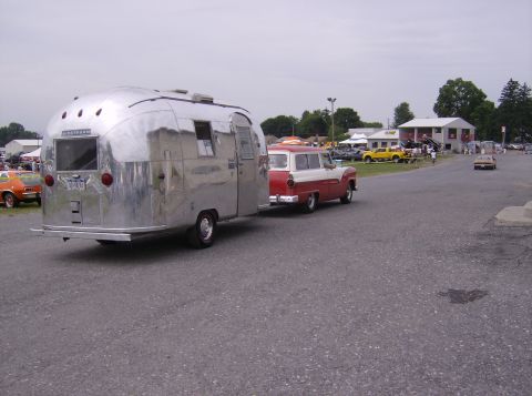 1970 Ford Ranchero - A classic red and white Ford station wagon pulls a shiny Airstream trailer down a paved road.