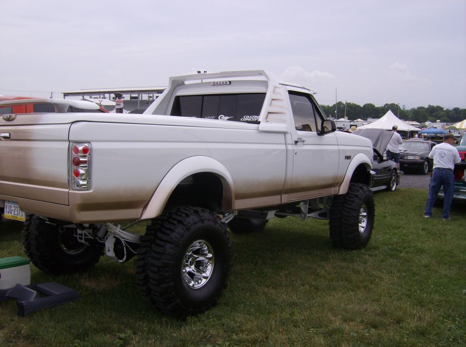 Lifted white pickup truck with custom rear spoiler and large tires