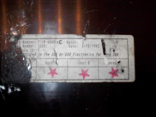 Worn Ford electronics factory label with part number 93FM-6000-AC and red star test stamps
