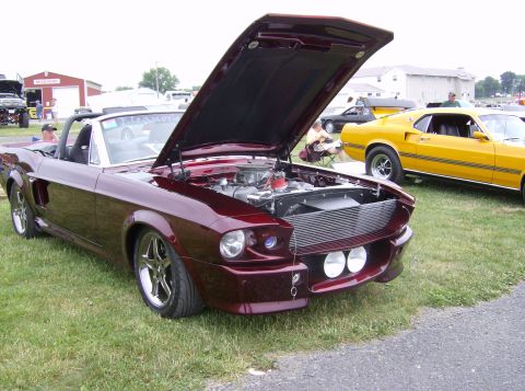 1970 Ford Ranchero - A maroon 1967 Ford Mustang convertible is displayed with its hood open, parked on grass next to a yellow car.