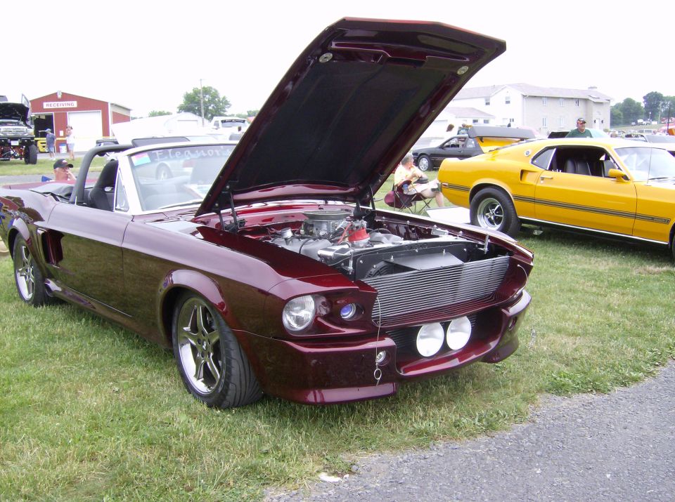 Maroon 1967 Ford Mustang convertible with hood open, showing engine. Chrome wheels, custom grille