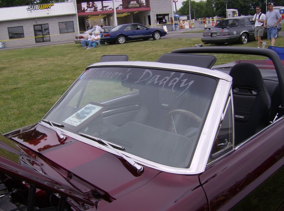 Maroon convertible interior with 'Winner's Daddy' on windshield
