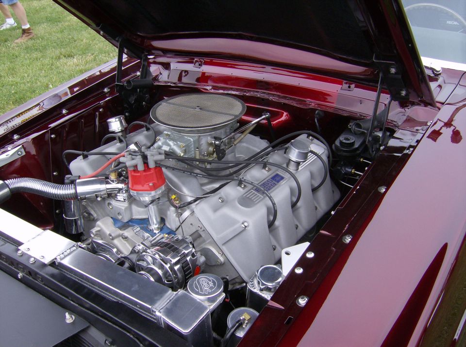 Engine bay of a custom car, showing a V8 engine with aftermarket intake and chrome alternator