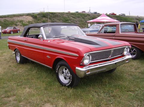 1970 Ford Ranchero - A red convertible coupe with black racing stripes and chrome wheels is parked on grass, with other vehicles and tents in the background.