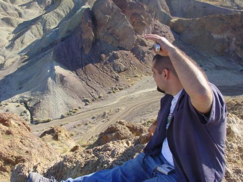 1994 Ford Bronco - Man captures a desert landscape with his phone, sitting on a rocky outcrop.