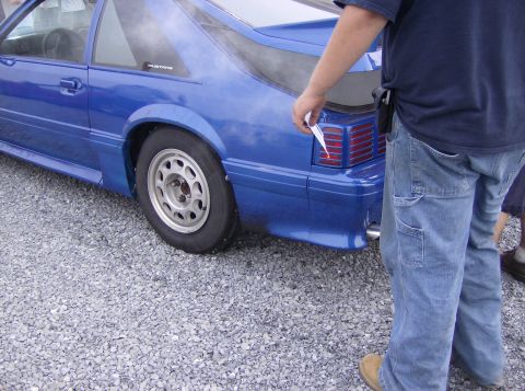 1970 Ford Ranchero - A blue coupe is viewed from the rear, with a person standing nearby holding a white slip of paper.