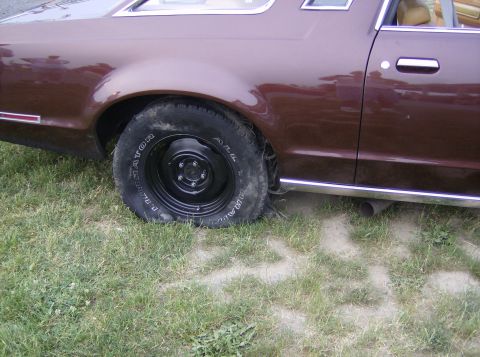 1970 Ford Ranchero - The rear quarter panel and wheel of a brown coupe are shown parked on grass.