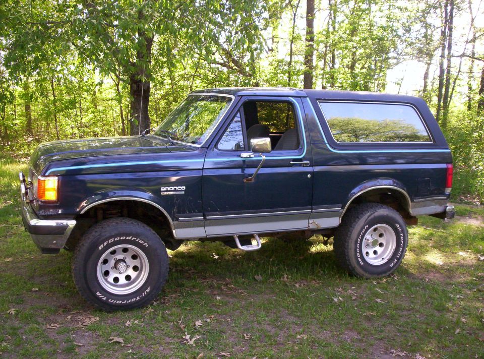 Dark blue 1990 Ford Bronco with silver trim and BFGoodrich tires parked on grass