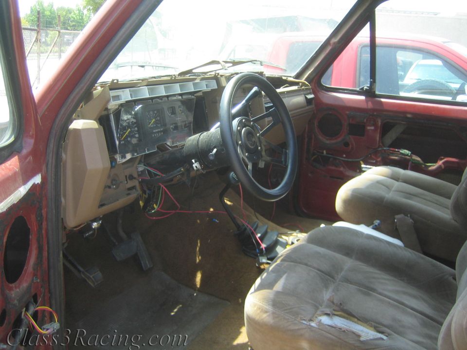 Stripped truck interior with steering wheel, gauge cluster and cloth seats